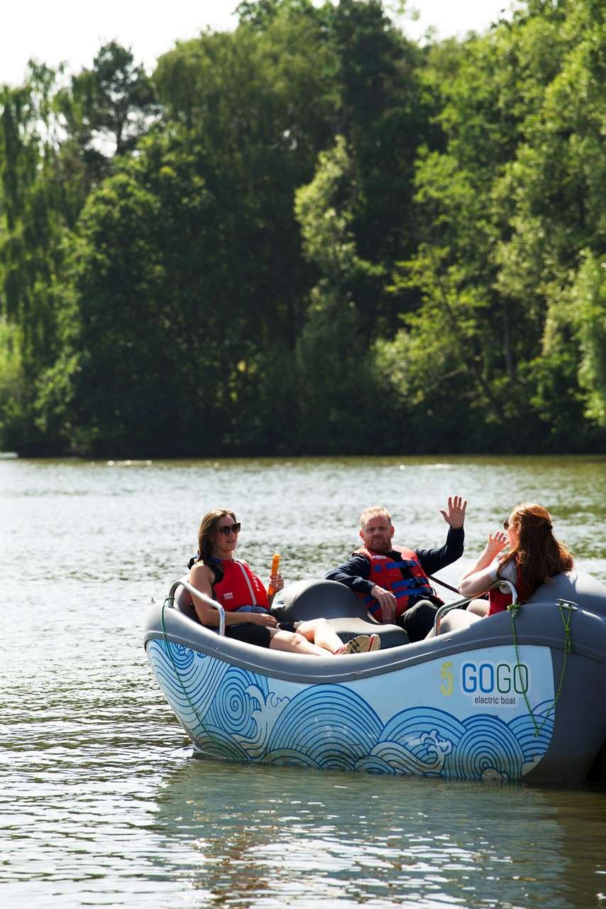 Wenham mortgage delegates waving from an electric boat on the lake in the sunshine.