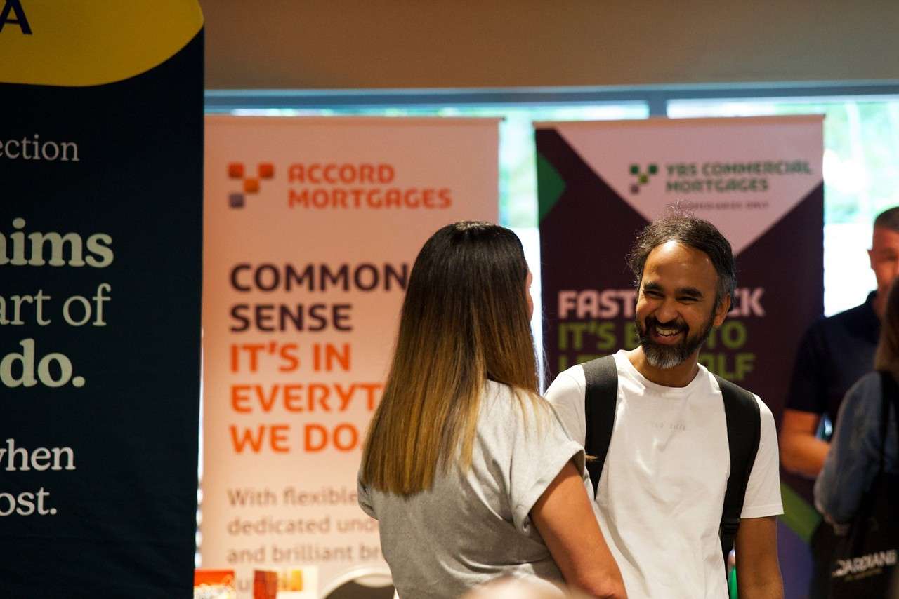 a man and a woman smiling at each other whilst chatting at a corporate event