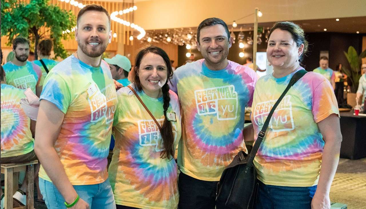 YuLife staff stood together wearing colourful tie-dye t-shirts.