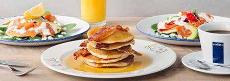 A selection of breakfast meals including American style pancakes with maple syrup and bacon