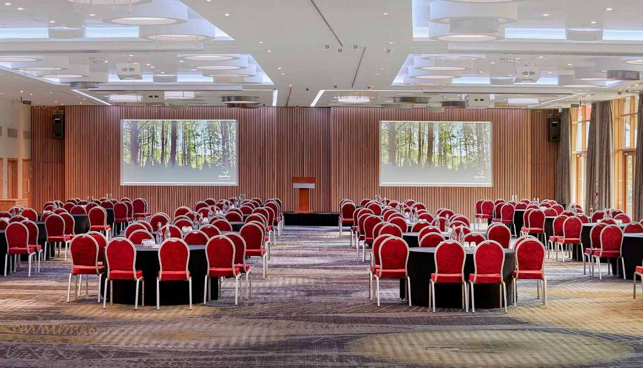 Chairs and tables facing the stage and screens at The Warren Suite at The Venue, Woburn Forest.