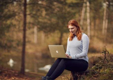 Delegate using her laptop in the forest.