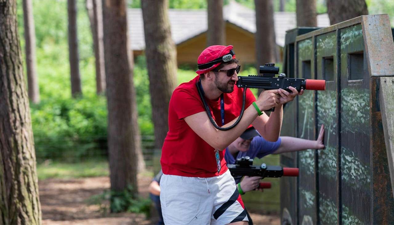 Man holding a laser gun hiding behind a wall in Laser Combat.