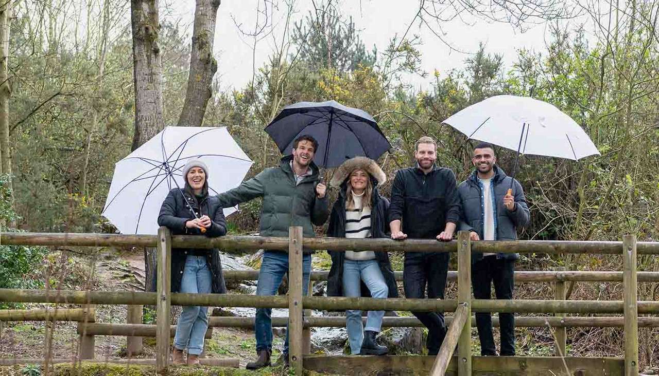 Delegates stood in the forest with umbrella's