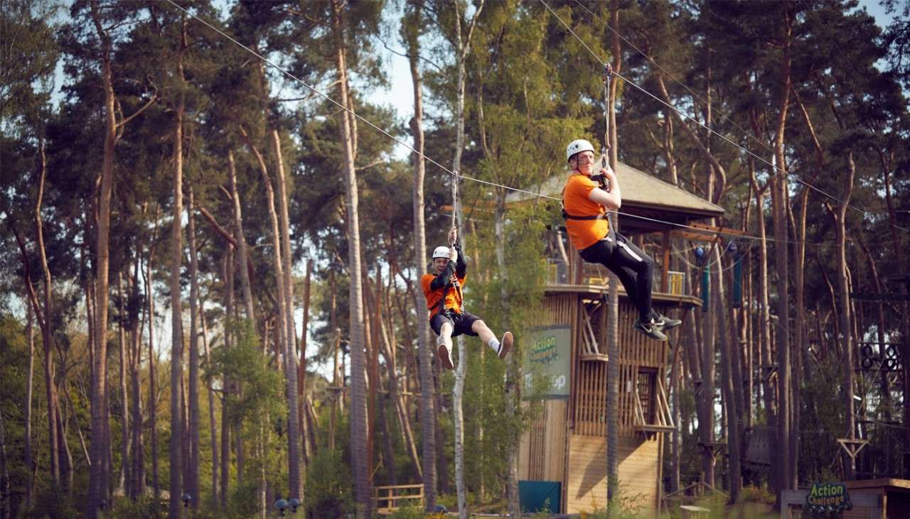 Two people on the zip wire through the forest