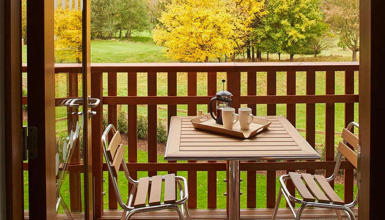 Table set up with coffee on an apartment balcony with a view of the forest