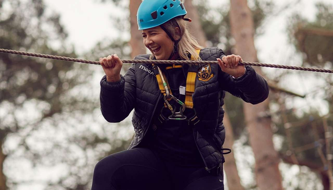 Woman balancing across ropes in the treetops