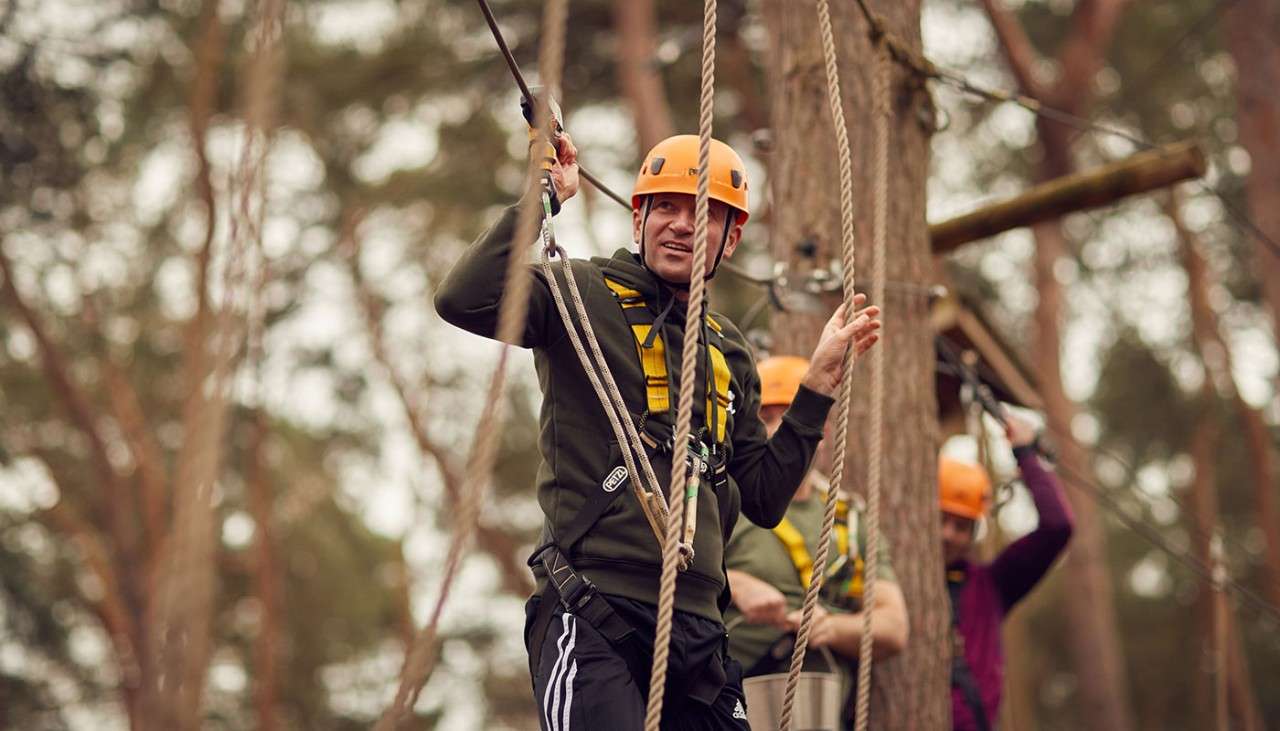 Man preparing to step across treetop obstacles