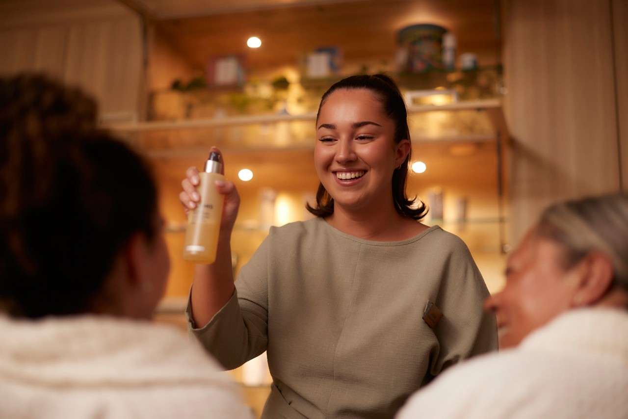 Therapist holding product bottle and demonstrating to clients 