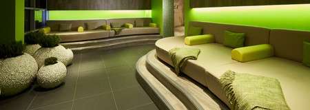 Curved green lounging area with throw cushions.
